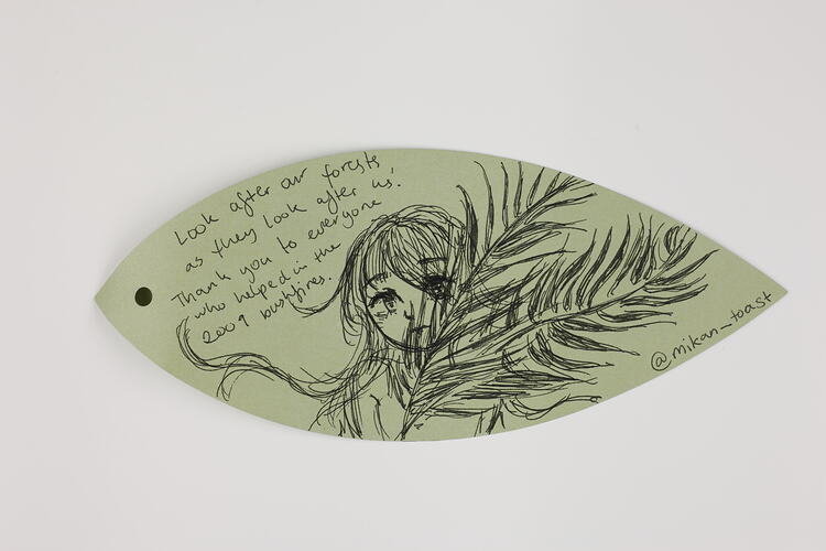 Green paper leaf with handwritten text and illustration in black ink.