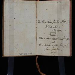 Open book with handwritten cursive text on right side. Pink cloth tape page marker.
