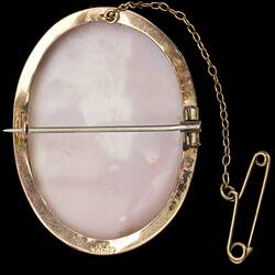 Back of oval white brooch with cameo of female bust in gold setting with safety chain. Horizontal bar.