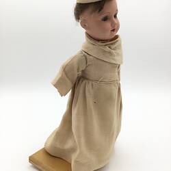 A doll dressed as a Benedictine Monk in a pale brown cassock and cap