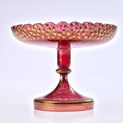 Red glass base/stand of epergne. Shaped like one piece plate on stand. Gilded decoration.