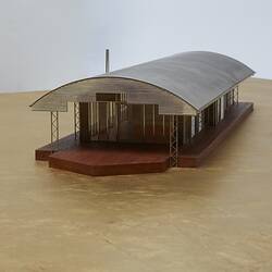 Model of a house with an arched roof, corrugated iron and wide expanses of glass.