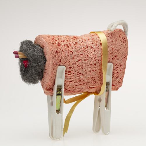 Toy sheep made from folded orange dishwashing sponge, steel wool ball, matches, white pegs.