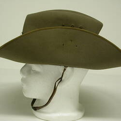 Green khaki hat with brim pinned to crown and chin strap, side view.