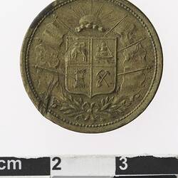 Round medal with rising sun, above coat of arms, above decorative leaf motif.
