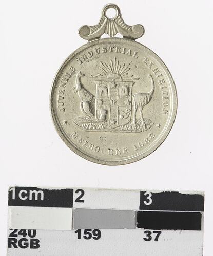 Round silver coloured medal with Australian coat of arms and text surrounding.