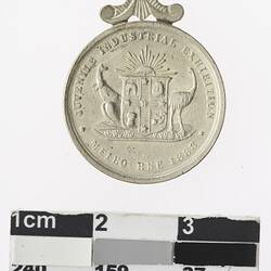 Round silver coloured medal with Australian coat of arms and text surrounding.