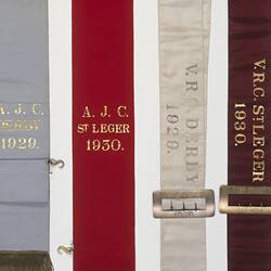 Detail of four ribbon sashes with gold or silver lettering.