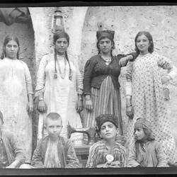 Group portrait with four women standing behind four children sitting on the ground.