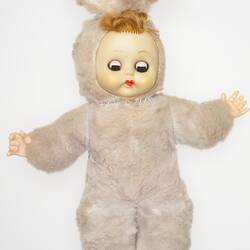 Doll with vinyl face and hands with pale pink cloth bunny suit body and synthetic hair. Eyes closed.
