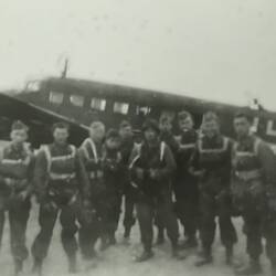 Group of serviceman standing in front of a plain.