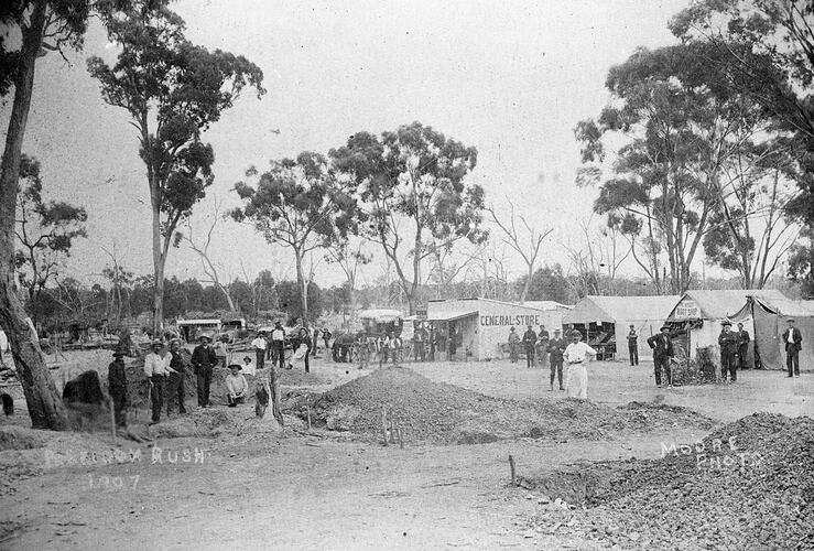 Group posing in front of goldfields settlement. Tents and trees in background.