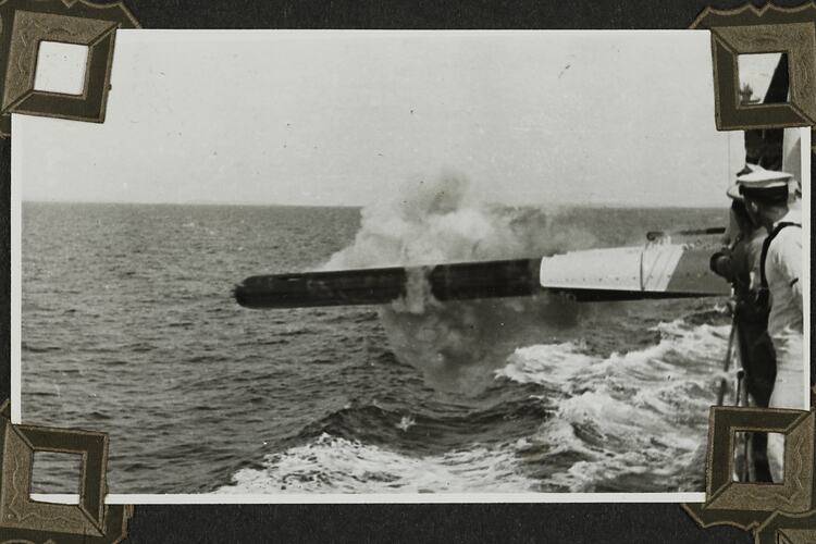 Torpedo being fired from ship and seaman standing in right foreground.