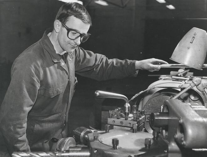 A man wearing safety glasses is operating a turet lathe.