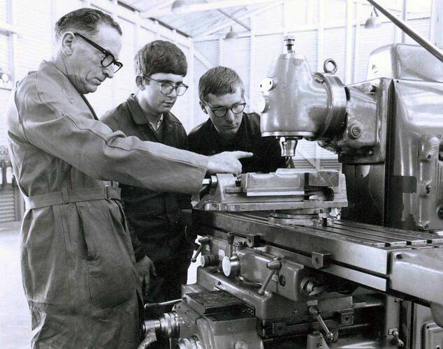 Three men in front of milling machine.