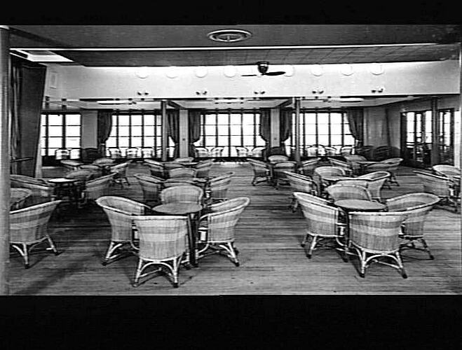 Ship interior. Room with round cane chairs and square tables.