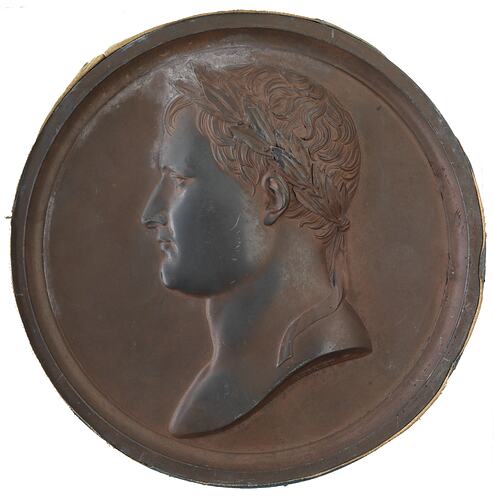 Round medal with male profile facing left.