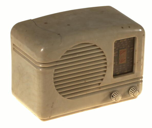 Cream plastic radio with circular speaker, two small knobs for tuning and display panel on front.