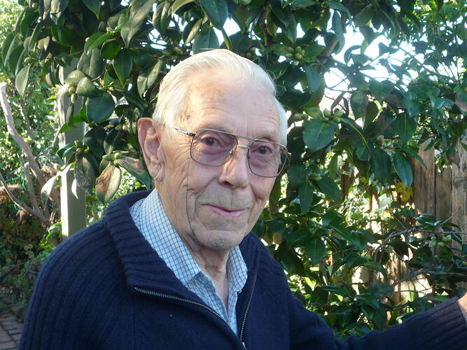 Elderly man in front of tree.