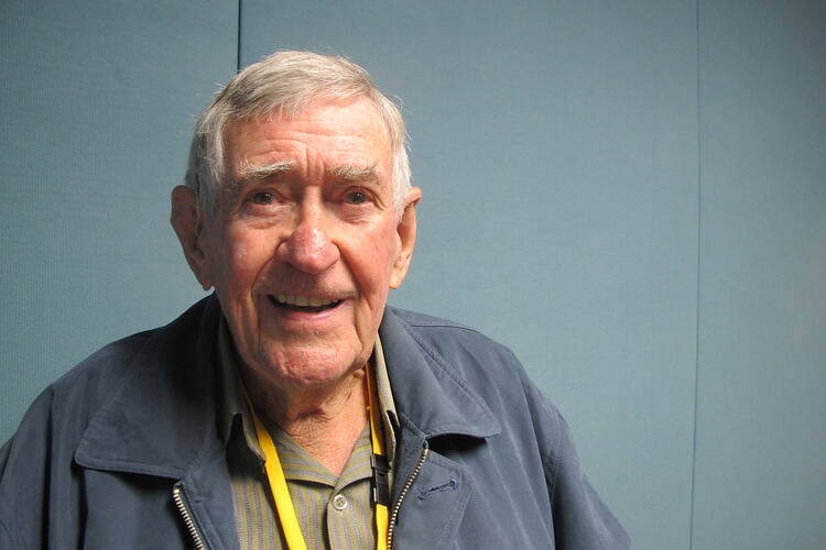 Elderly man in blue jacket and yellow lanyard.