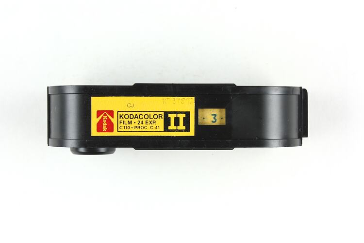 Black plastic film cartridge with sticker label.