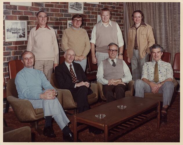 Two rows of men smiling in lounge area.