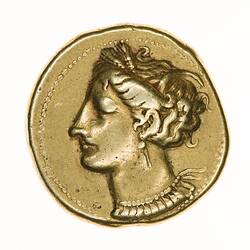 Irregular round gold coin with head of Tanit wreathed with corn facing left.