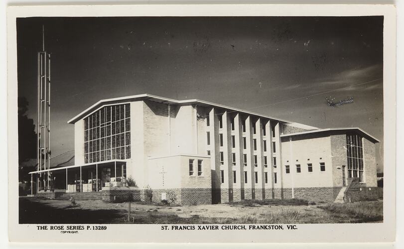 Exterior of white church with side annexe visible. Metal tower with cross at left.