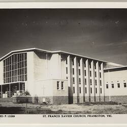Exterior of white church with side annexe visible. Metal tower with cross at left.