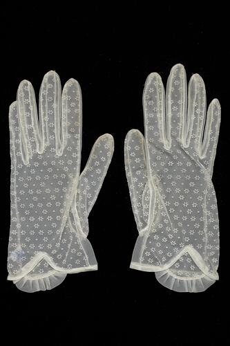Wrist length gloves made from white netting with floral pattern.