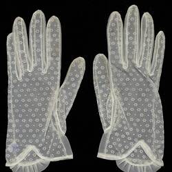 Wrist length gloves made from white netting with floral pattern.