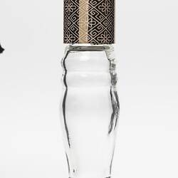 Curved glass perfume bottle, gold plastic lid. Lid has geometric design.