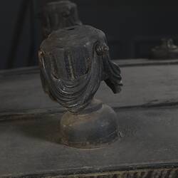 Black wooden hearse, detail of decorative woodwork. Urn with draped cloth.