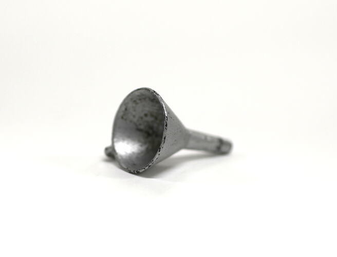 Side view of tiny metal funnel.