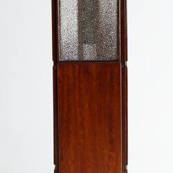 Back of wooden passenger lift model. Opaque glass window in top section. Handle at top right.