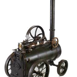 Model of black moveable steam engine on four wheels with tall chimney at front.