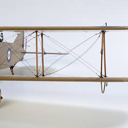Model biplane aeroplane painted mustard brown. Front view of left wing.