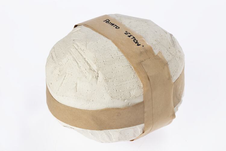 Round plaster mould with brown tape around top and side. Black writing on tape.