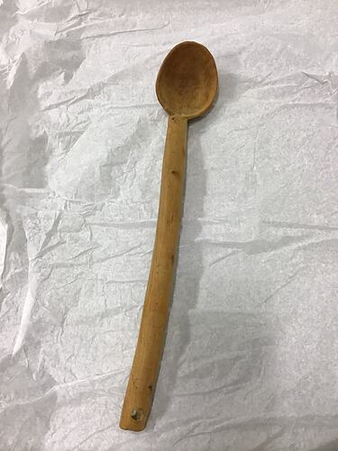 Wooden spoon with long handle, small oval bowl shape at tip.