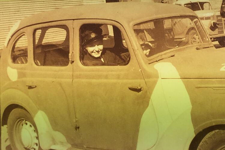 Woman in uniform driving car.