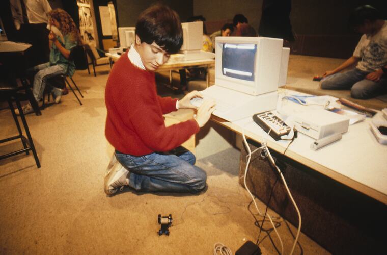 Student programming Lego machine on the floor.