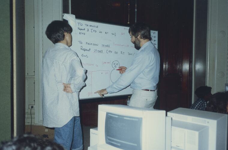 Male student and teacher working at a whiteboard.