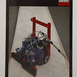 Front cover LEGO build in red, blue and black. Wheeled and grey cable. Text above.