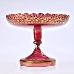 Red glass base/stand of epergne. Shaped like one piece plate on stand. Gilded decoration.