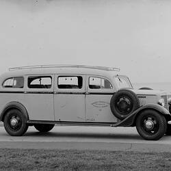 Motor bus with grass in foreground, water (ocean?) in background.