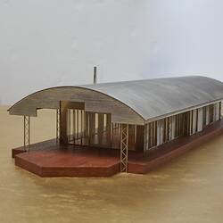 Model of a house with an arched roof, corrugated iron and wide expanses of glass.