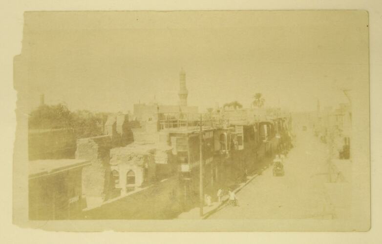View of street with vehicles, people and minaret.