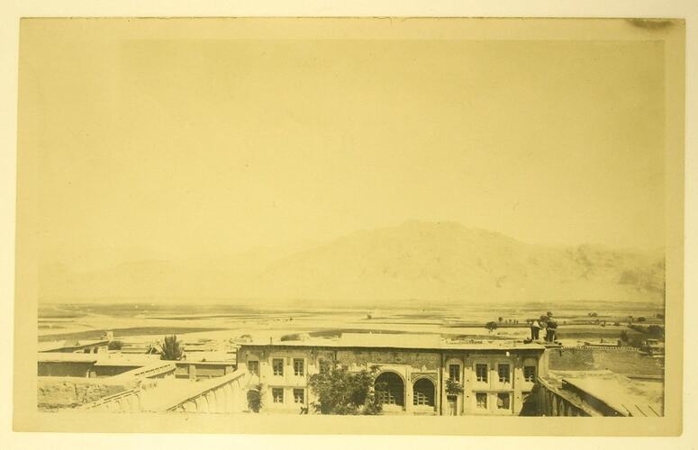 Elevated view of city, plains and mountains in background.