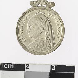 Round silver coloured medal with profile of crowned woman, with text surrounding.