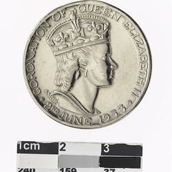 Round silver coloured medal with profile of crowned woman and text surrounding.